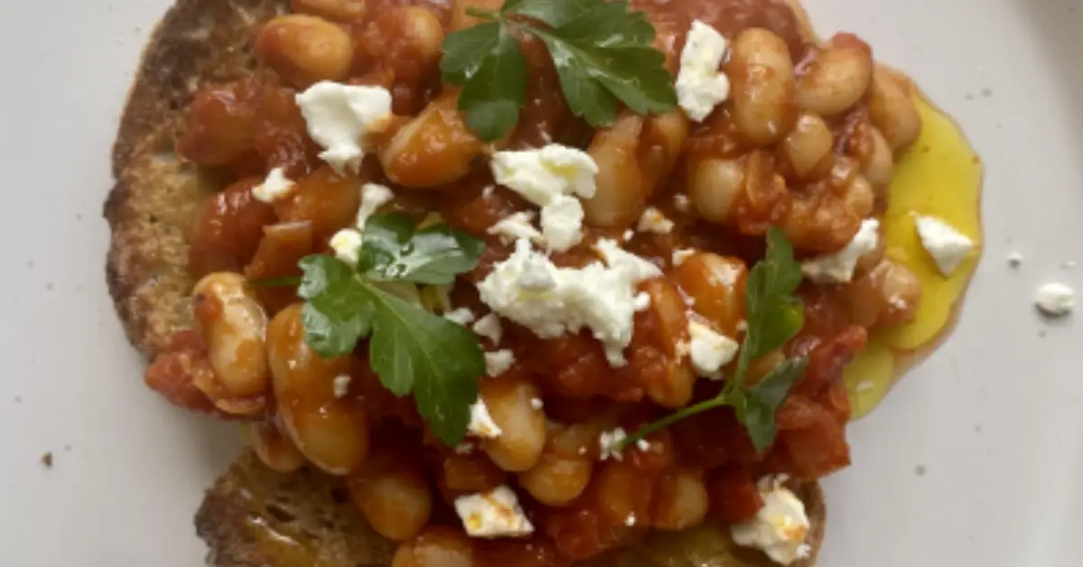 Beans in a rich tomato sauce served on toast with crumbled cheese, parsley and a drizzle of Yare Valley rapeseed oil.