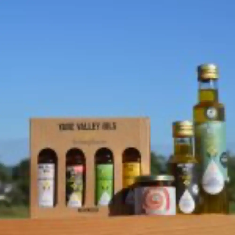 Yare Valley Oils gift set with assorted rapeseed oils and chutney displayed outdoors against a countryside background.